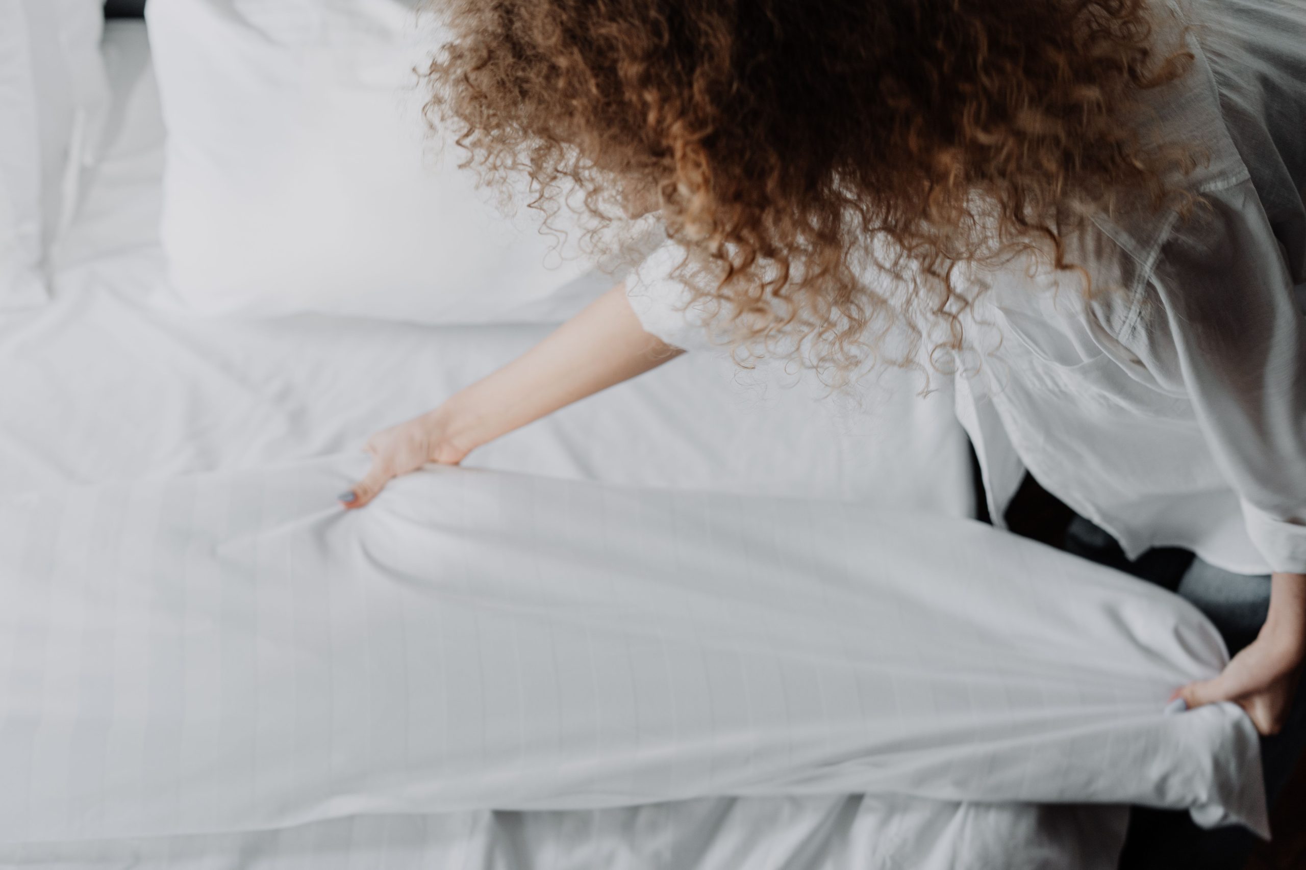 Personne pliant des draps blancs dans une chambre sereine